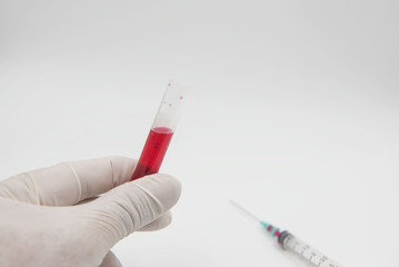 sample blood tube in hand and syringe on a white background. Medical equipment. 