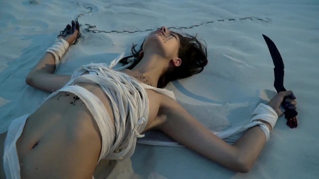 A woman mummy lies on the sand