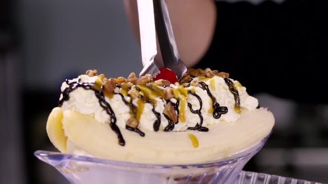 Closeup Of Banana Split, Woman Places Cherry On Top 