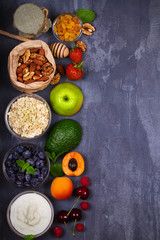 Bowls of Yogurt and Oat Flakes, Fruits, Honey and Summer Berries. View from above, top studio shot of fruit background. Flat lay setup made of selection of healthy food, copy space