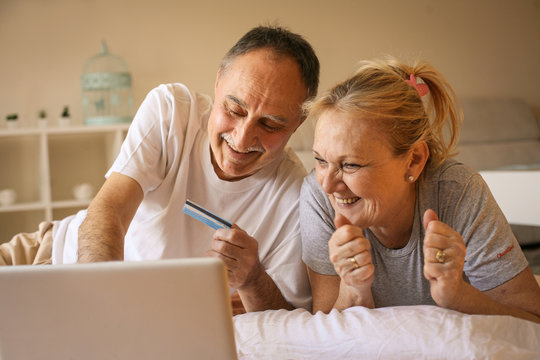 Senior Couple Using Laptop In Bed.