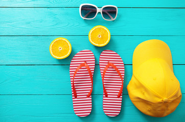 red striped flip flops, red sunglasses and orange fruit on blue wooden background. Top view and...