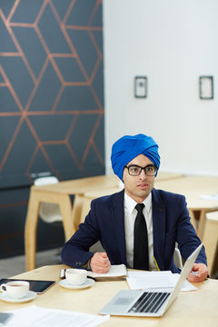 Businessman Or Tv Newscaster In Turban Sitting By Workplace