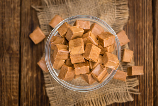 Portion of Caramel pieces on wooden background (selective focus)