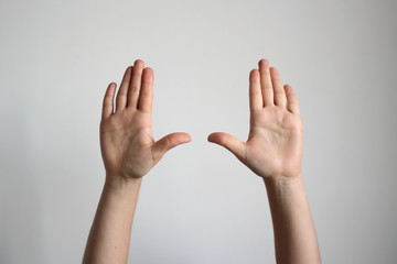 Young woman's fold one's palm isolated on light gray background. Gesture