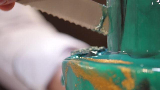 The pastry chef cut the cake with a long knife. Cut a turquoise cake. The pastry chef cut the cake