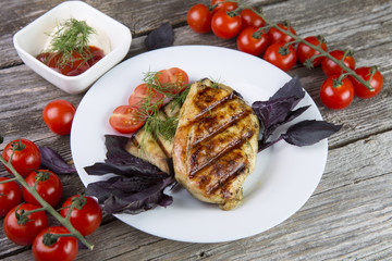 Chicken steak with grilled vegetables, tomatoes, oregano, on wooden background