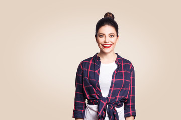 Portrait of beautiful happy girl in casual style looking at camera with toothy smile. studio shot on beige background.