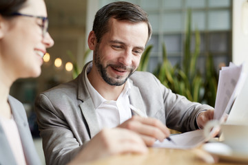 Happy man signing business document after negotiating