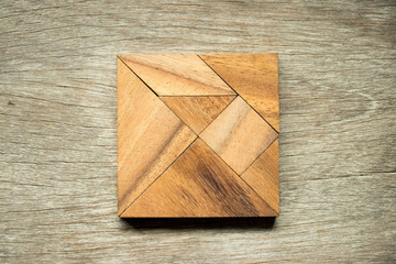 Tangram puzzle in square shape on wooden background