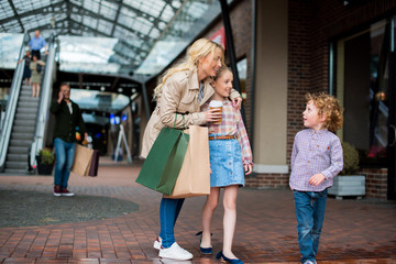 Naklejka premium young mother talking with her little kids during shopping at shopping centre