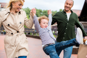 Fototapeta premium smiling family holding hands and having fun while walking on the street