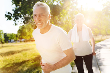 Cheerful retired man jogging with his wife