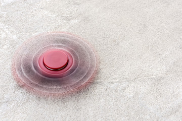 Fototapeta na wymiar Red fidget spinner in motion stress relieving toy on concrete background.