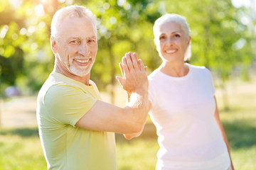 Positive senior couple giving high five outdoors