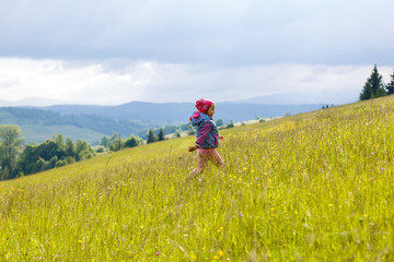 A little girl is running around the mountains