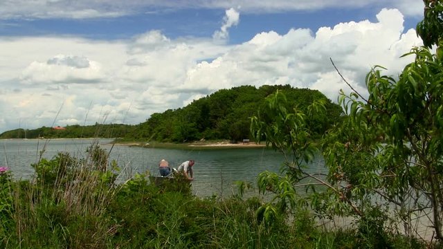 Two elderly retired men return in motor boat from fishing trip at Bennets Neck Pocasset Bourne Cape Cod