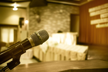 Microphone on podium with abstract blurred of conference hall or seminar room event background,...