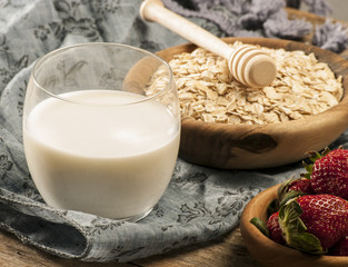 Healthy breakfast concept with oat flakes and fresh berries on rustic background. Food made of granola and musli. Healthy banana smoothie with blackberries, honey and milk.