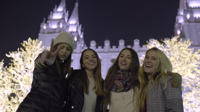 Happy Young Women Pose For Portrait In Front Of LDS Temple (Lit For Christmas) In Salt Lake City, Utah