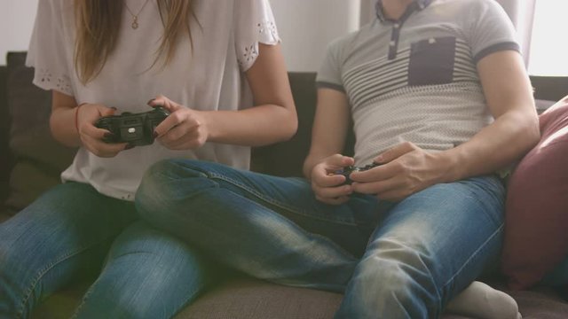 Young attractive couple in love playing video game while sitting on sofa in the living room and feeling so happy. Close up shot.