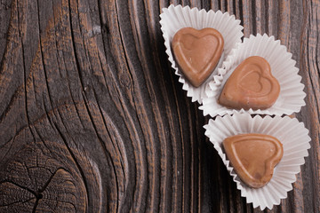 Chocolate heart-shaped candy on wooden background