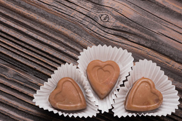 Fototapeta na wymiar Chocolate heart-shaped candy on wooden background
