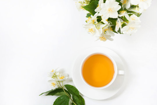 Jasmine flowers and cup of green tea on white. Top view and concept. Teatime.