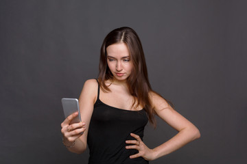 Fototapeta premium Joyful young woman taking selfie by her smartphone