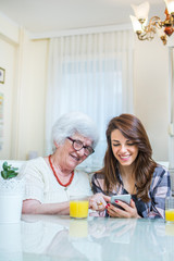 Grandmother and granddaughter commenting social media feeds on smart phone.