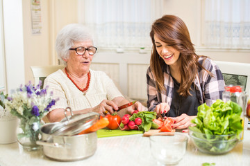 Grand-mère et petite-fille préparant la nourriture à la maison.