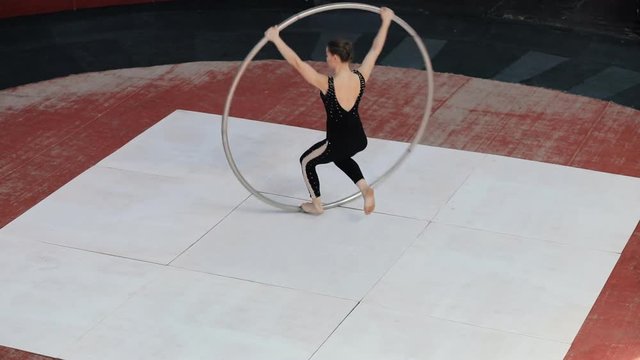 Skilled professional circus artist training with a big cyr wheel on stage