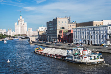 Barge with sand on Moskva river with skyscraper building view, Moscow