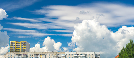 Panoramic view of bright picturesque white clouds over city in summer afternoon