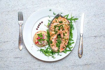 Baked salmon with vegetables and rice on the plate. Knife and fork cutlery. Top view