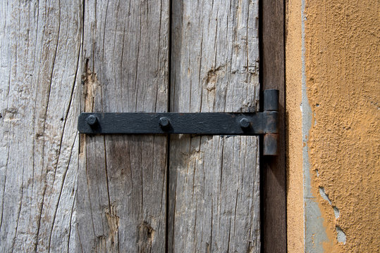 Old metal hinge and nut fixed on wooden door
