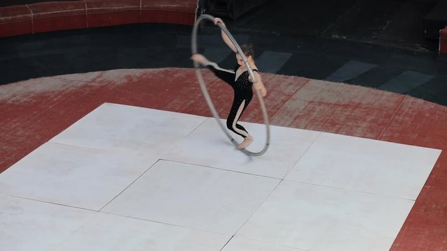 Skilled professional circus artist training with a big cyr wheel on stage