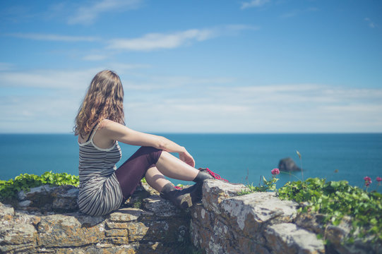 Woman relaxing on wall by the sea