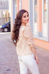 Young beautiful woman brunette walks at the city in Europe. Summer. Happy girl. Street fashion.