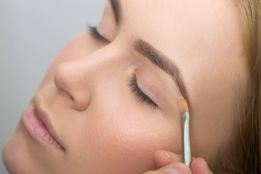 Girl with closed eyes getting makeup on eyelids