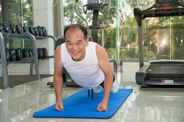 senior man fitness exercising by doing push ups in the fitness center or gym, sport and health concept.