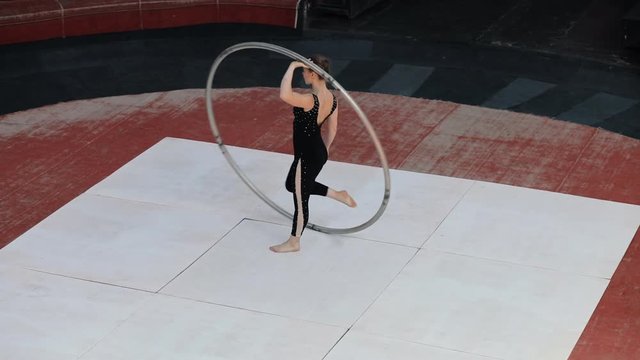 Skilled professional circus artist training with a big cyr wheel on stage at slow motion