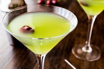 Appletini Cocktail with cherry on wooden surface.