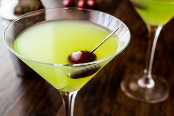 Appletini Cocktail with cherry on wooden surface.