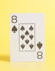 Playing card eight of spades on yellow background