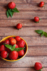 Juicy fresh strawberries in a bowl on wooden background, selective focus