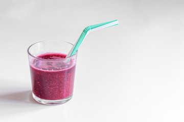 Raspberry cocktail in little cup with blue drinking straw. Clear background.