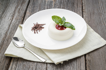 dessert named panacota. With chocolate and jam, on a wooden table