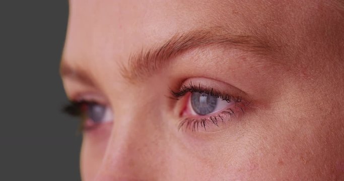 Close up of beautiful woman with blue eyes on grey background.