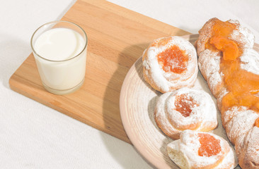 Appetizing homemade buns with orange fruit jam with milk
